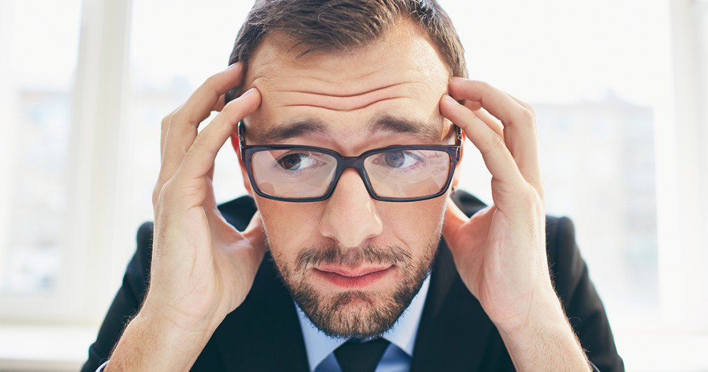 Frustrated businessman in eyeglasses touching his head